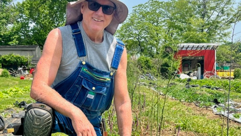 Professor 凯文凯利 smiling while kneeling in a garden